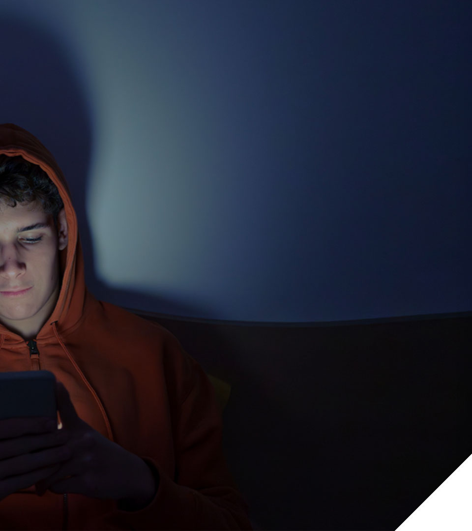 young man alone in dark room scrolling through his phone